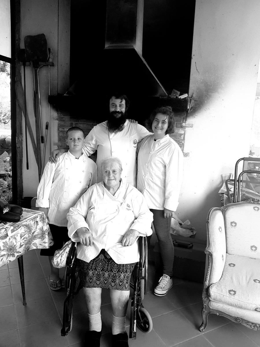 Tre generazioni della famiglia dell'Osteria dalla Nana Vecia davanti al camino